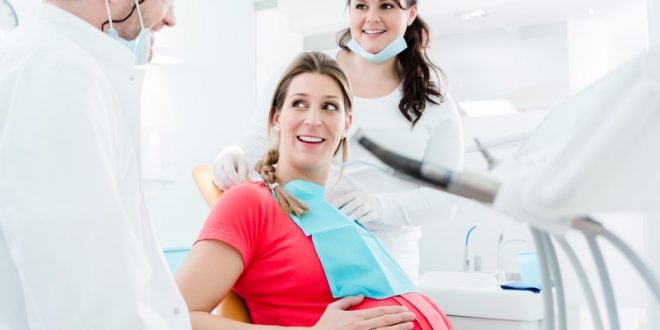 Pregnant woman at dentist before treatment Donna incinta durante la visita odontoiatrica con dentista e assistente