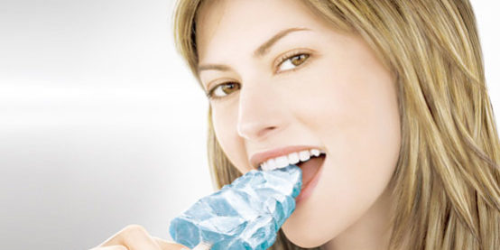 denti-sensibili donna che morde un cubetto di ghiaccio