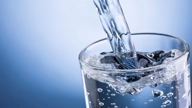 acqua-fluoro acqua che viene versata in un bicchiere trasparente
